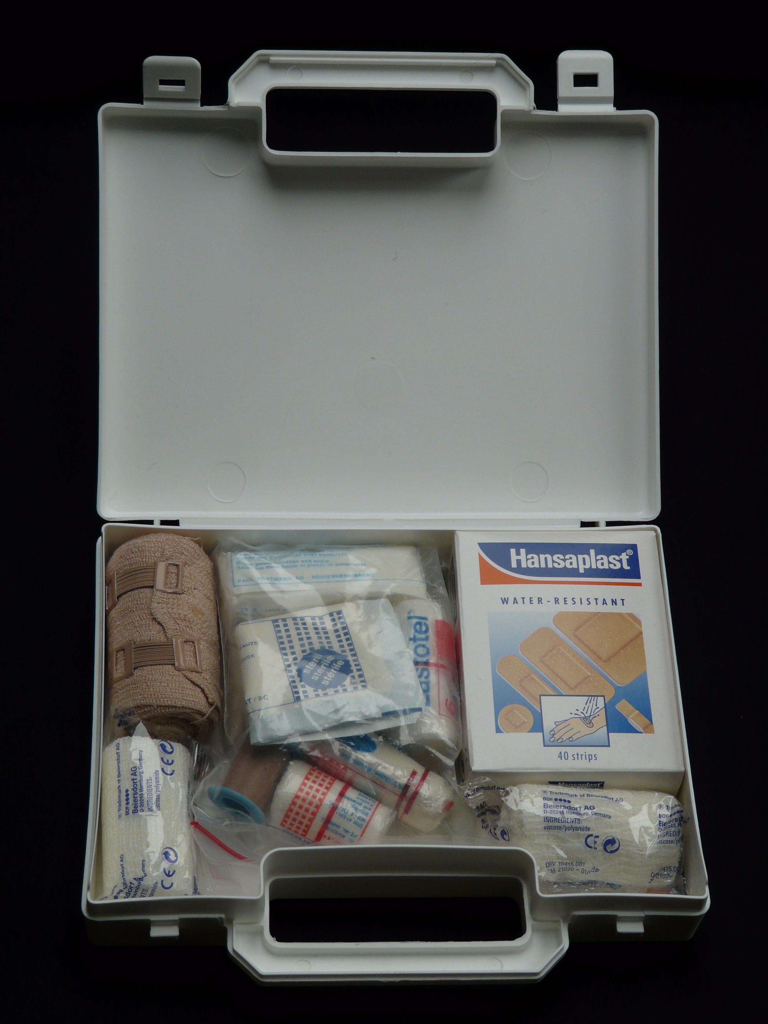 White first aid kit full of bandaids on a black background